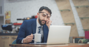 A man sits with his laptop, thinking about how to start a business.