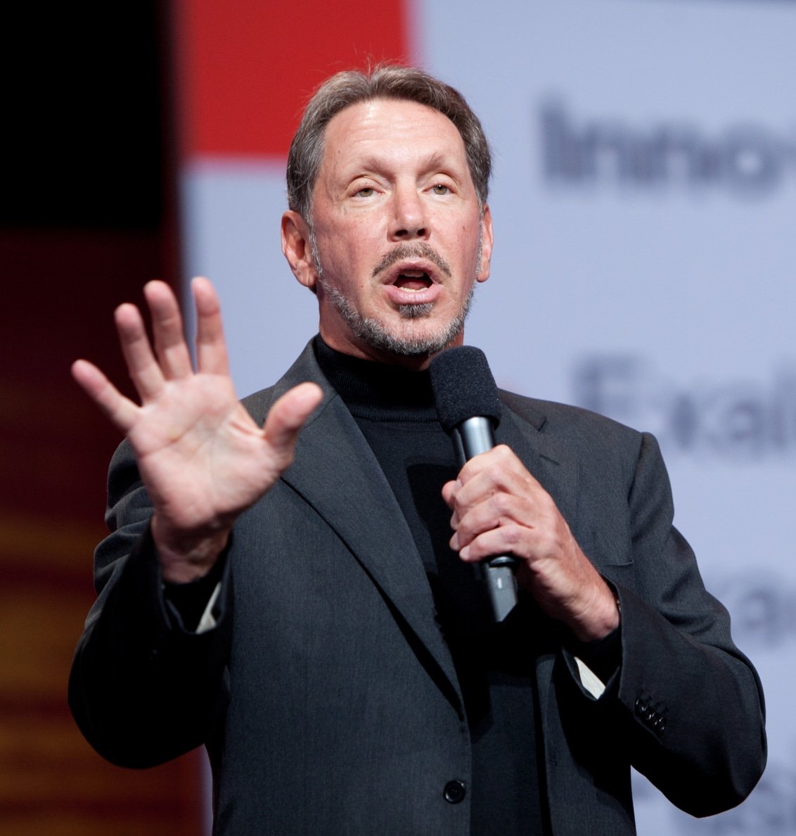 Image of Larry Ellison speaking with microphone on stage. Image is used to highlight Larry Ellison Quotes in this article.